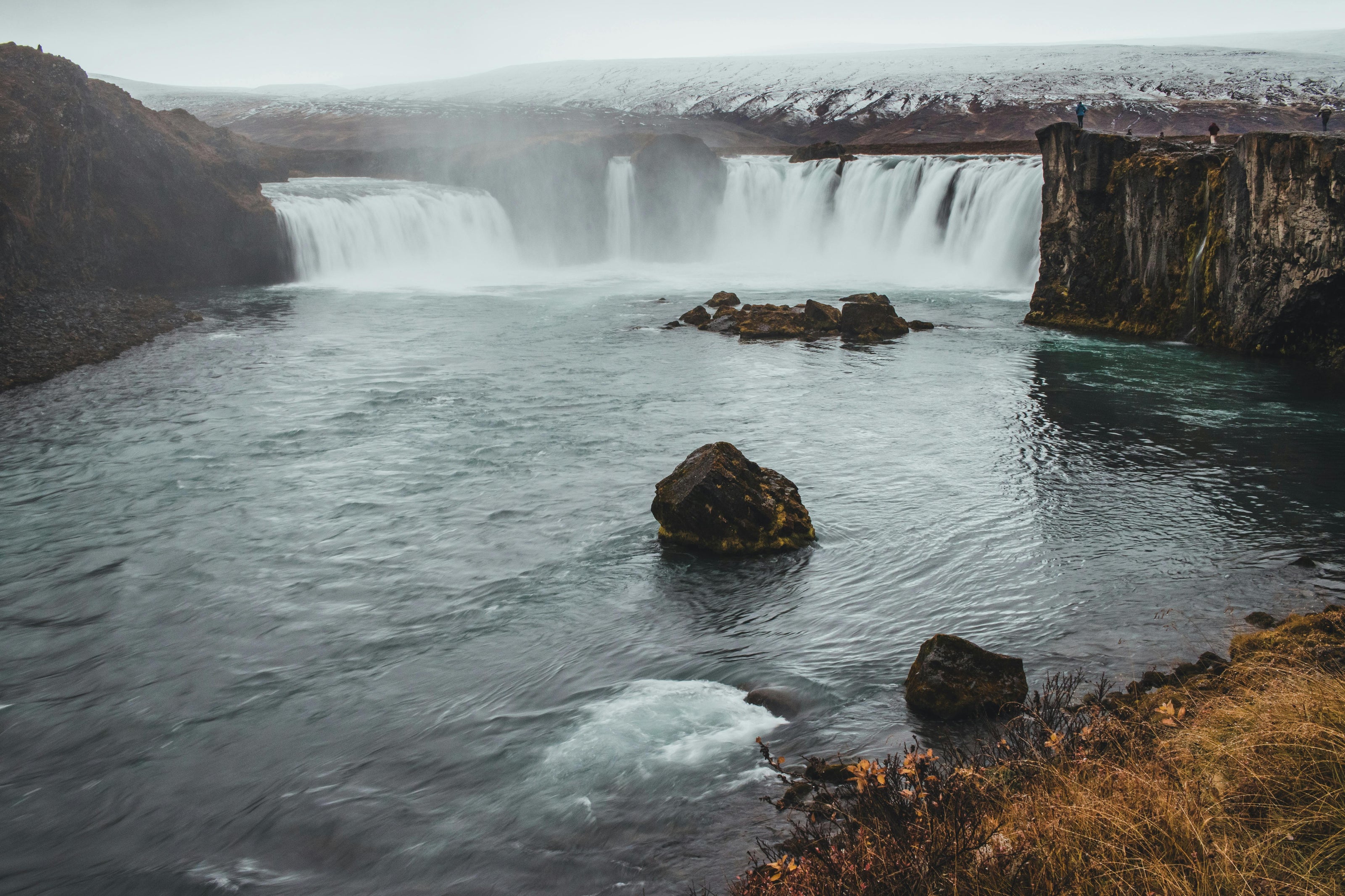Waterfall cascading into a river with rocky landscape